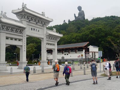 Walking group moving towards Po Lin Monastery with big buddha statue at top of peak in distance, Hong Kong