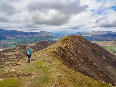 Single person on Ramble Worldwide walking holiday atop of Scar Crags towards ridge of fell, with Causey Pike in view