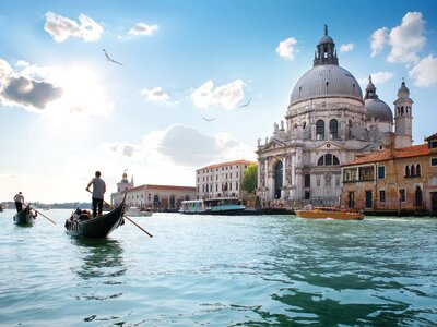 People poling along a canal in front of beautiful buildings, Venice, Italy