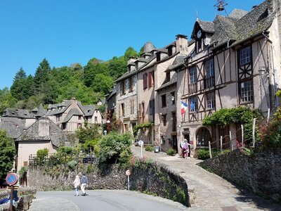 Traditional French houses curving round bend of stone footpath on sunny day in Conques, France