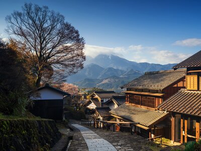 Traditional Japanese houses along descending hill on Nakasendo Way with mountains in distant background, Japan