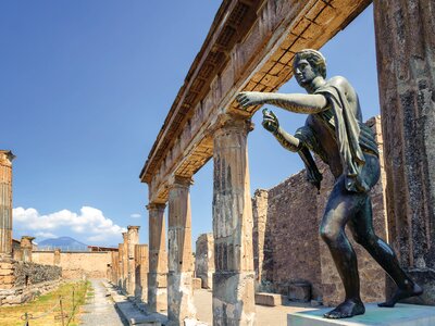 Temple of Apollo with bronze statue of Apollo  reaching out from beneath stone pillars in Pompeii, Naples, Italy, Europe