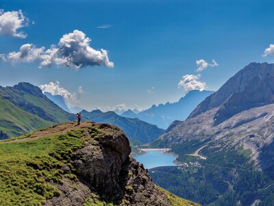 Solo walker near edge of cliff face taking in mountainous scenery, Dolomites, Italy, Europe