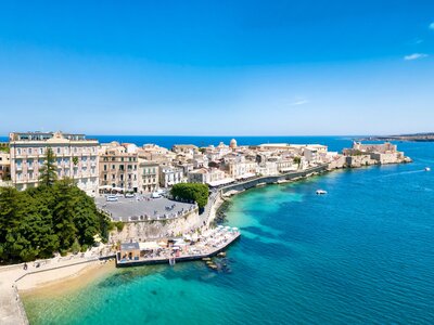 distant panoramic view of Ortigia with turquoise waters surrounding, Syracuse, Italy