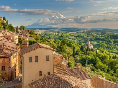 Traditional village and stone houses looking out over green, forested hill slopes, Tuscany in Italy