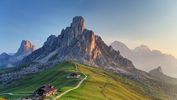 The craggy rock faces and peaks of the Dolomites in Italy, above a mountain lodge, bathed in sunshine