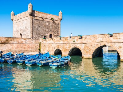 Essaouira harbour with blue painted boats moored by an arched bridge, Morocco