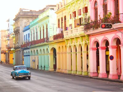 Vintage car driving down a street of colourful houses in Old Havana
