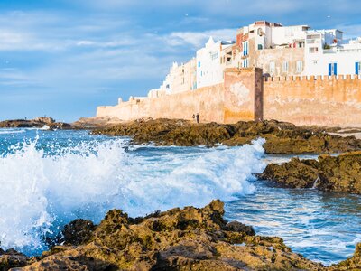 Essaouira city walls with waves breaking on rocky shore below, Morocco