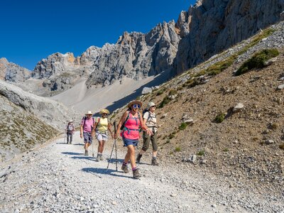 Walking group on Ramble Worldwide walking holiday ascending loose stone path exiting mountain valley in Picos De Europa, Spain