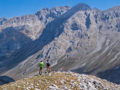 Distant view of Ramble Worldwide leader and hiker admiring scale of Picos De Europa mountain range, Spain