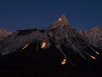 Night time shot of mountain with various depictions of Summer Solstice Fires at Tirol Zugspitz Arena, Austria
