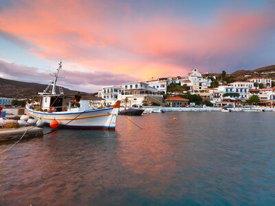 Batsi village during sunset on the coast of Andros island in Greece with boat docked in foreground