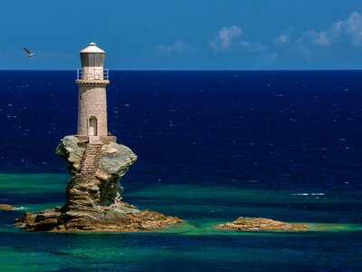 Lighthouse Tourlitis of Chora in Andros island and a seagull flying near lighthouse, Cyclades, Greece