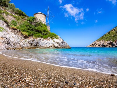 Gialia beach with old windmill in Alonnisos island, Greece