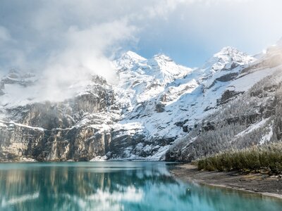 Early winter with first snow at mountain lake Oeschinensee with sun shining, Switzerland
