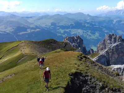 Ramble Worldwide walking holiday group ascending grassy mountain ridge in Saaser Calanda and background of Grison Alps, Switzerland