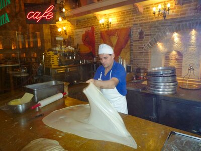 Pastry chef at Bougatsadiko Psirri restaurant in Greece moving dough with hands for Bougatsa pie creation