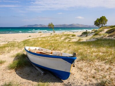 Boat on sandy and grassy Marmari beach on the Greek island of Kos on sunny day, Greece