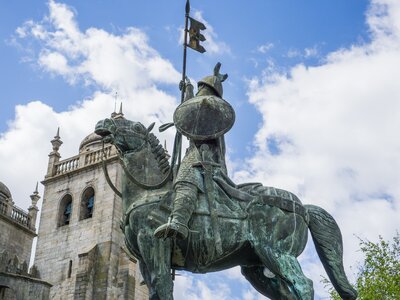 Statue of Vimara Peres man on horseback with sword, shield, and holding flag outside front of Porto cathedral in Porto, Portugal