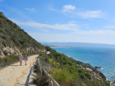 Two women on Ramble Worldwide walking holiday enjoying conversation whilst on coastal path incline on sunny day in Spain