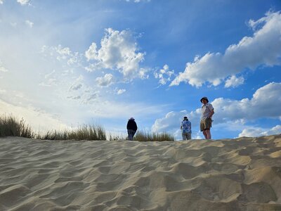 Trio of walkers standing on sand with blue sky and white clouds behind, Donana national park, Andalusia, Spain