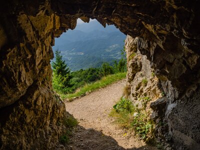 Tunnel Exit on Road of 52 Tunnels on the Pasubio massif in Veneto revealing green landscape with grass and pine trees across sloping hills, Italy