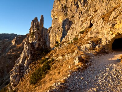 Strada delle 52 Gallerie, Road of 52 tunnels at sunset with golden glow casted over rocky mountainside face and dark tunnel in corner, Pasubio, Italy