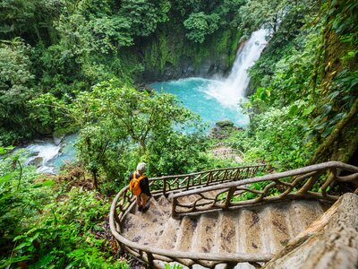 Person walking down stairs towards Rio Celeste waterfall in the Tenorio Volcano National Park rainforest jungle of Costa Rica, Central America