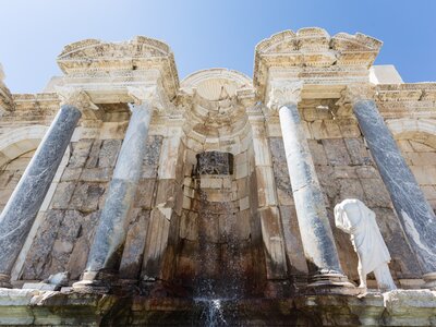 Ancient Antoninus Fountain of Sagalassos in Burdur with columns and partly broken white sculpture stood by fountain, Turkey