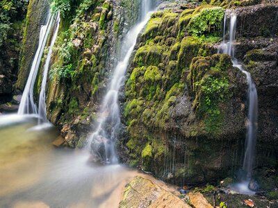 Close view of Varvara waterfalls trailing over mossy wet stone into body of water, Halkidiki, Greece