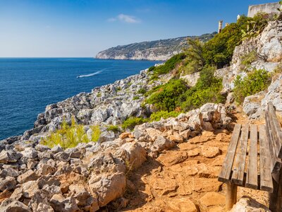 Scenic sea view from wooden bench  on rocky cliff of Salento, Italy