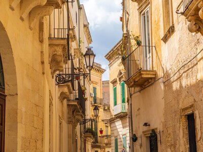 Stone buildings and iron balconies along a narrow street, Lecce, Apulia, Italy