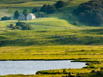 Landscape of the Aubrac plateau in France with farm, lake and meadows