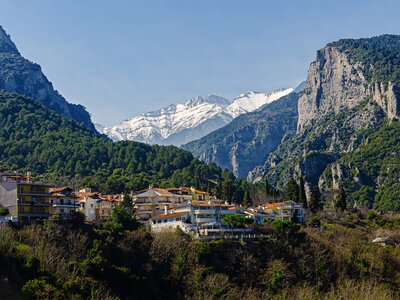 Mountains of Olympus viewed from centre of Litochoro with buildings nestled into mountainside and snow-capped mountains in far distance, Greece