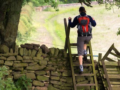 Hiker crossing a stile on the Hadrians Wall Walk in Northumberland, North East of England, UK