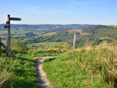 The Cleveland Way walking trail at Sutton Bank in the North York Moors with wooden signpost and background of expansive green countryside landscape