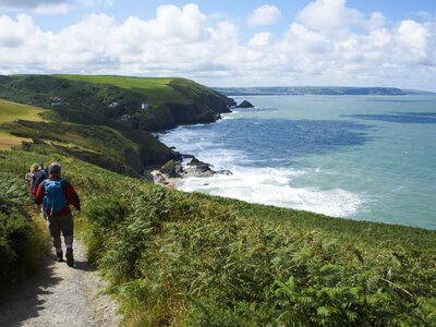 Walkers following coastal pathway on walking holiday trip Ceredigion & Pembrokeshire Coast, Wales, UK