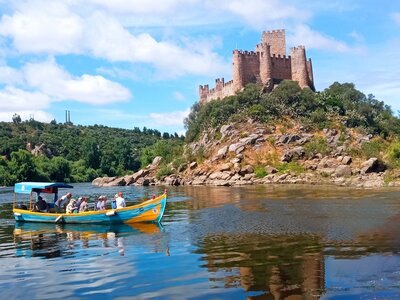 Ramble Worldwide adagio walking group on boat ride in body of water looking at medieval Almourol Castle atop hill in distance, Portugal