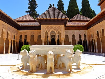 Moorish Style design of Alhambra Granada with outward facing statues of dogs holding basin of water fountain as centrepiece of Alhambra outdoor garden on sunny day, Andalusia, Spain, Europe