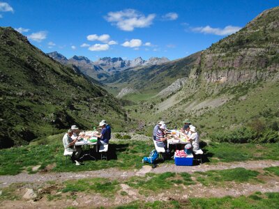 Ramble Worldwide walking group enjoying a picnic in the Pyrenees with vast mountain range in background, Spain