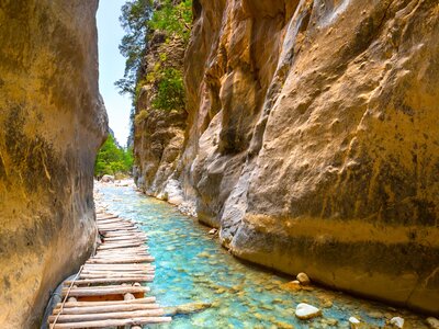 Wooden bridge over turquoise water at National Park Samaria Gorge, hiking trail, Crete, Greece