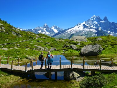 Hikers admiring Mont Blanc mountain range from wooden bridge in Aiguilles Rouges, French Alps, France, Europe