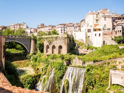 Villa Gregoriana and charming buildings in Tivoli with waterfall and green foliage, Italy