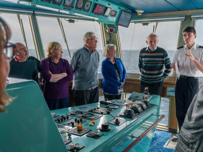 Ramble Worldwide walking holiday The Fjords of Norway group in Fred Olsen cruise ship control room receiving explanation from staff member on controls, Norwegian sea, Europe