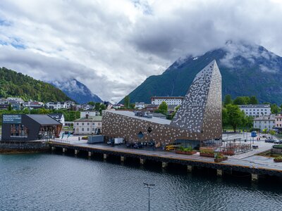 Andalsnes town with Visitor Centre building and cloud covered mountains seen from elevated view from Romsdalsfjord, Møre og Romsdal county, Norway