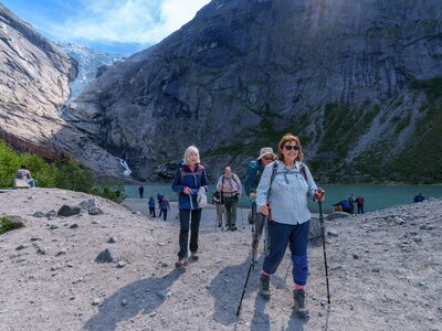 Happy Ramble Worldwide walking group walking away from Briksdalsbreen glacier on sunny day, Norway