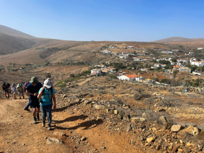 Ramble Worldwide group ascending hill with white-washed village in background, Fuerteventura