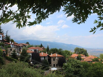 Litochoro town nestled within mountains with orange coloured house roofs popping out in contrast against green surroundings, Greece