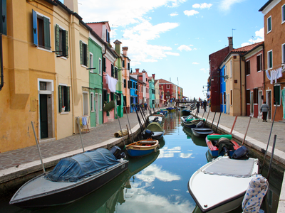 Colourful houses and canal with many boats on both sides docked along the edges, Venice, Italy